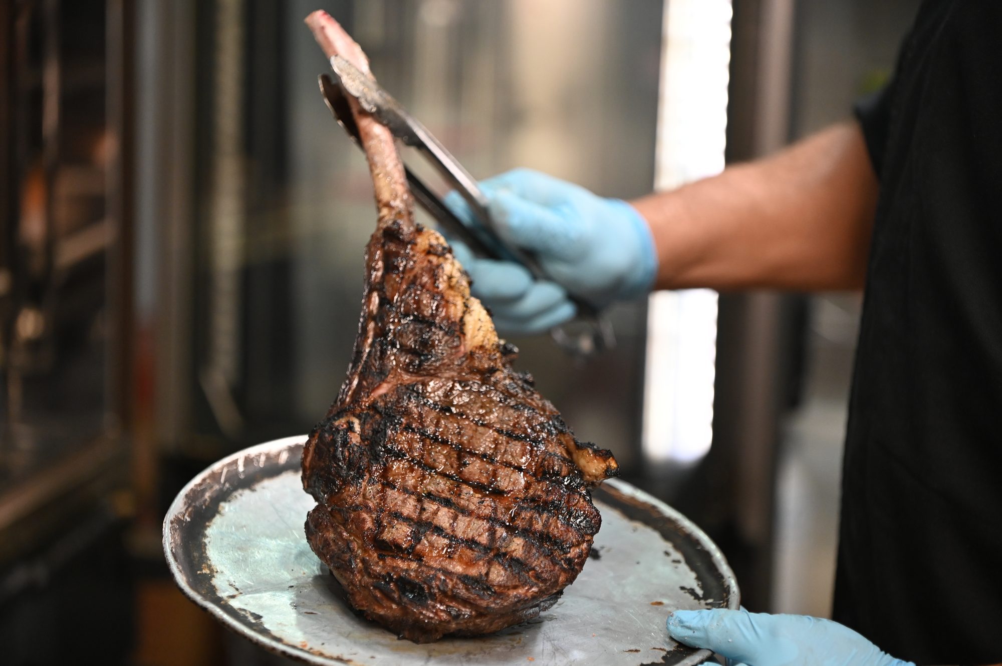 Tomahawk Black Angus recién salido de la parrilla, servido con guantes